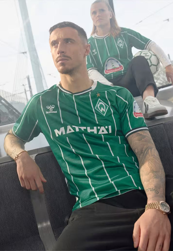 Marco Friedl wearing a green Werder Bremen 2025/26 Home jersey with visible branding, sitting in a vehicle.
