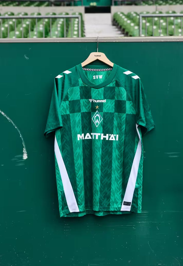 Green Werder Bremen jersey with white accents on a hanger against a green background